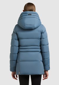 Svijetloplavi jakna s punjenjem i kapuljačom, s horizontalnim sašivenim dijelovima i oznakom loga na stražnjoj strani. Glatki, vodootporni materijal.