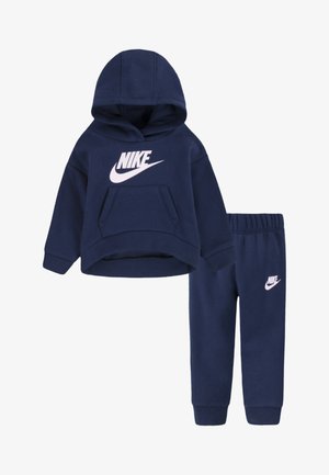 Conjunto de moletom e calças de algodão azul-marinho, com um bolso frontal e o logótipo da Nike em branco em ambas as peças. Textura suave, ajuste descontraído.