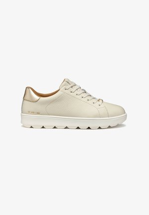 Zapatilla de cuero crema de perfil bajo con cordones blancos, suela estriada blanca y acento dorado metálico en el collar del talón.