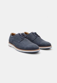 Navy suede lace-up shoes with a smooth texture, contrasting white midsole, and subtle red and blue accents on the tongue.