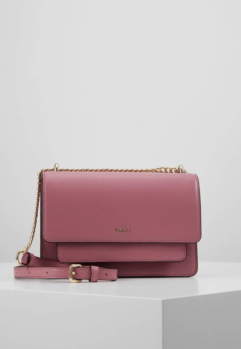 Borsa a tracolla in pelle rosa con catena e pattina anteriore. Presenta un logo in oro e una forma rettangolare con superficie testurizzata.