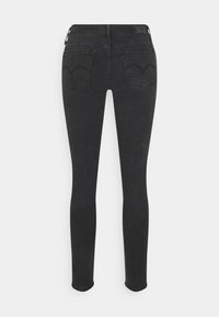 Jeans skinny negros con una textura de denim suave, que presentan dos bolsillos traseros con un diseño de costura distintivo, abertura de pierna estrecha y sin adornos.