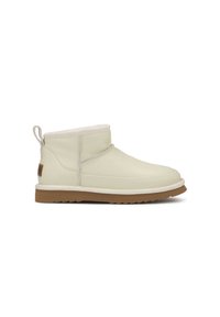 Botas de tobillo de cuero crema con un forro suave, suela de goma plana, punta redondeada y una lengüeta en la parte posterior para facilitar el uso.