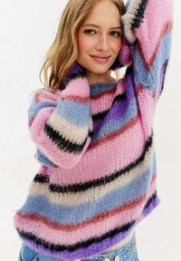 Mužský svetr z vícebarevné příze s pruhy v růžové, modré a krémové barvě, volného střihu, s vroubkovanými manžetami a měkkou, nadýchanou texturou.