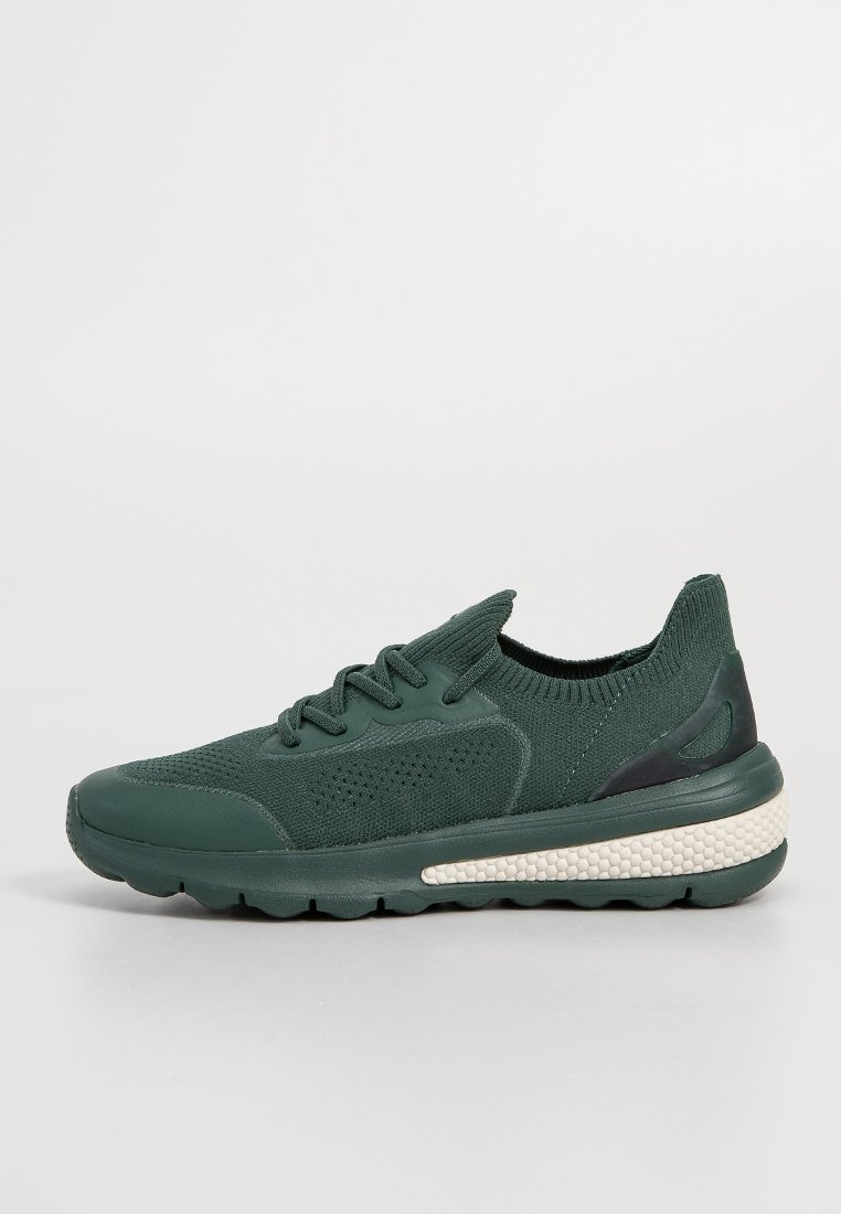 Grüne Strick-Sneaker mit einer strukturierten Oberfläche, runder Spitze und schwarzem Fersenakzent. Gerillte Sohle mit einem cremefarbenen Zwischensohlen-Detail.