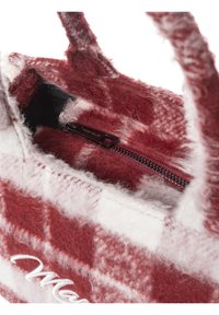 Rote und weiß karierte Felltasche mit kurzen Griffen, ausgestattet mit einer Reißverschlusstasche im Inneren. Innen mit weichem Stoff gefüttert. Markenname sichtbar.