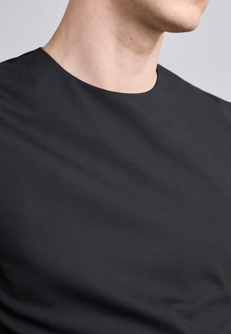 Black crew-neck t-shirt featuring a smooth texture and a fitted design, with visible stitching and a simple, clean silhouette.