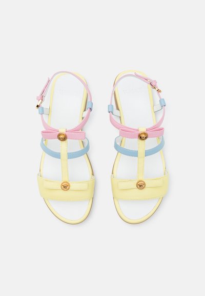 Sandalias coloridas con tiras amarillas, rosas y azules, detalles en dorado, suela plana y correas ajustables en el tobillo. Acabado suave.