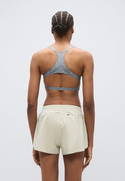 Γκρι αθλητικό σουτιέν με μοτίβο και σχεδιασμό racerback, συνδυασμένο με ανοιχτό μπεζ σορτς με ελαστική μέση και μικρή πίσω τσέπη.