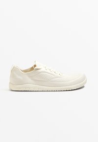 White knit sneaker with a breathable, textured surface; low profile; flat sole with flexible grooves; minimalistic lace-up design.