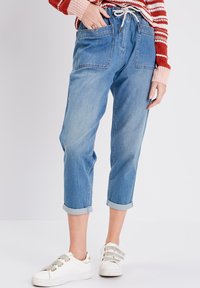 Pantalons en denim bleu clair avec une coupe décontractée, taille élastique à cordon de serrage et ourlets retroussés. Comprend deux poches avant et une texture lisse.