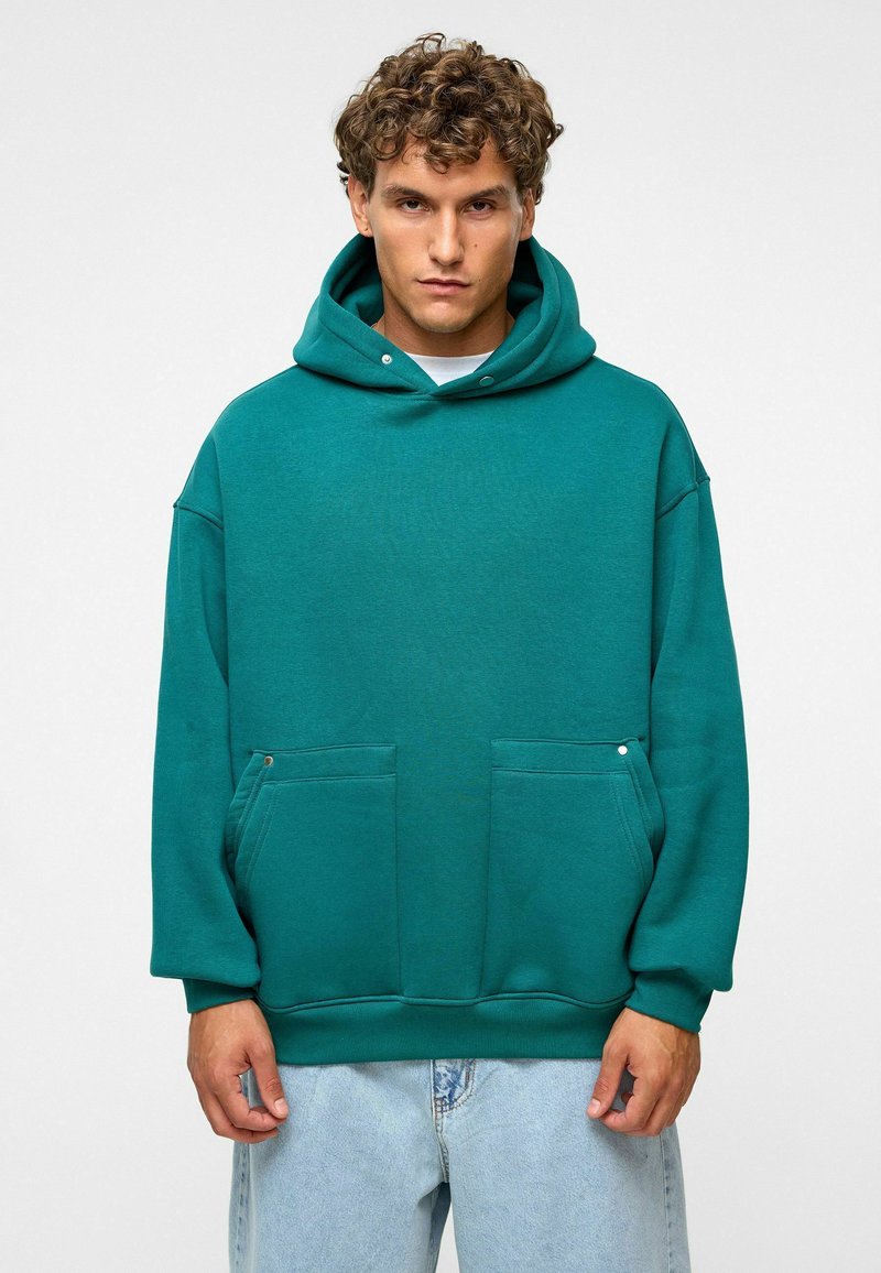 Teal katoenen hoodie met een ruime kangoeroe-pocket, ribgebreide manchetten en zoom. Voorzien van een trekkoordkap en een ontspannen pasvorm.