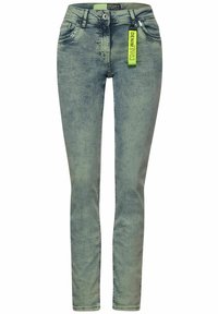 Jeans skinny in denim verde sbiadito, con chiusura a bottone, cinque tasche e un etichetta verde brillante con la scritta "DENIM".