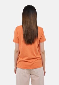 T-shirt orange à manches courtes avec une coupe décontractée, fabriqué en coton doux, avec un col rond et une texture lisse.
