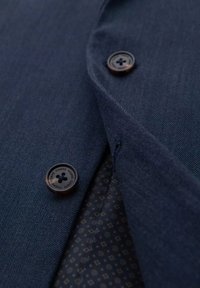 Ciemnoniebieska marynarka w jodełkę z brązowymi guzikami, z widocznym kontrastowym wzorem podszewki i klapami.