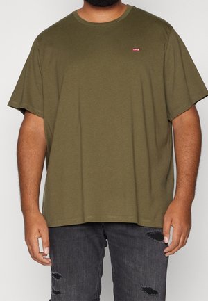 Mand iført en olivengrøn Levi's t-shirt med korte ærmer og sorte slidte jeans, stående foran en ensfarvet baggrund.