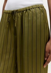 Olijfgroene, lichtgewicht stof broek met zwarte verticale strepen, elastische tailleband met trekkoord en zijzakken.