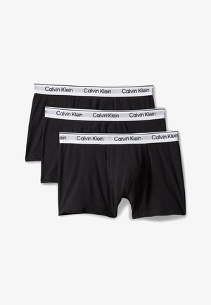 Trzy czarne bokserki Calvin Klein z białymi elastycznymi pasami w talii z logo Calvin Klein czarnym tekstem.