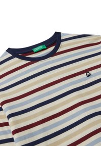Pruhované bavlněné tričko s střídajícími se námořnickými, béžovými a burgundskými pruhy. Kulatý výstřih a malé vyšívané logo na hrudi.
