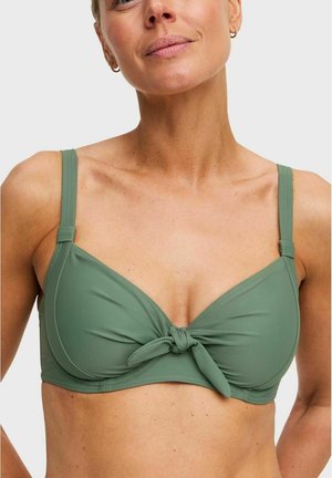 Vrouw draagt een groene bikini top met knoopdetail in het midden en verstelbare schouderbandjes, tegen een effen lichte achtergrond.