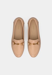 Mocassins en cuir beige avec un bout arrondi, des détails en métal doré, des coutures discrètes et une texture lisse, avec une semelle intérieure de marque.