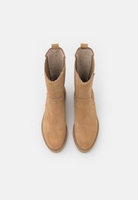 Tan suede ankle boots with a smooth texture, a low heel, and pull tabs on the back for easy wear. Minimalist design with no embellishments.