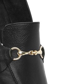 Stivale in pelle nera con superficie texturizzata, caratterizzato da un accento in metallo dorato e un design superiore strutturato.
