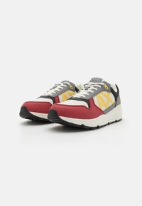 Red and gray athletic shoes with leather and mesh upper, featuring a yellow logo, white laces, and a black rubber sole.
