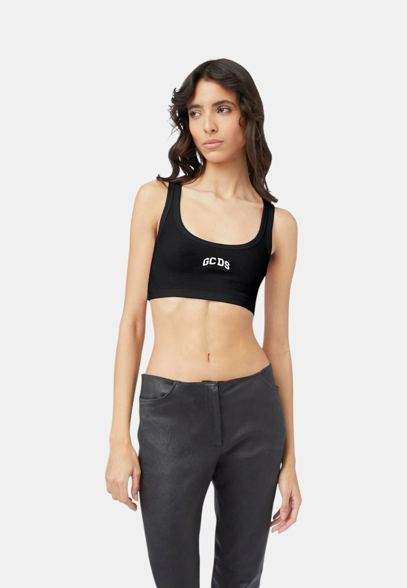 Top corto nero in tessuto liscio con logo GCDS; presenta spalline larghe e un design aderente. Abbinato a pantaloni neri.