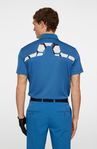 Herrblå pikétröja med korta ärmar, med geometrisk svart och vit ryggdetalj och mjukt, lätt tyg.