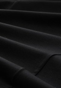 Black fabric with a smooth texture featuring horizontal pleats. Material appears soft and thick, showing subtle light reflection.