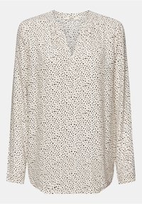 Blouse blanche à manches longues avec motif de pois noirs irréguliers, encolure en V et détail de tissu froncé près du col.