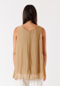 Top marrone senza maniche con scollatura a V e tessuto liscio. Presenta una silhouette fluida e un leggero contrasto all'orlo nella parte inferiore.