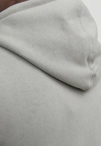 Light gray hoodie featuring a smooth texture, soft fabric, and a rounded hood, showcasing stitching details and a casual design.