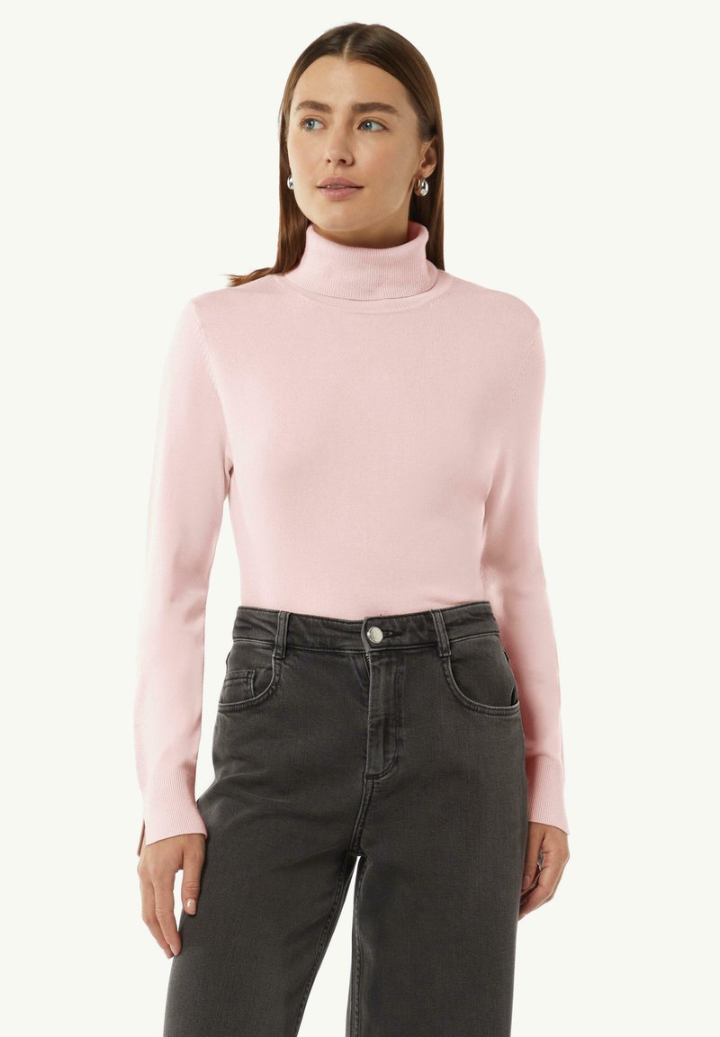 Helles rosa Rollkragensweatshirt mit langen Ärmeln, geripptem Kragen und glatter Textur, kombiniert mit hochgeschnittenen, dunkelgrauen Jeans mit Taschen.
