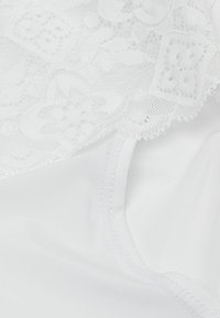 Weiße Unterwäsche mit einem floralen Spitzeinsatz oben, glatt satinierter Stoff darunter und einem zarten gestickten Rand entlang der Nähte.