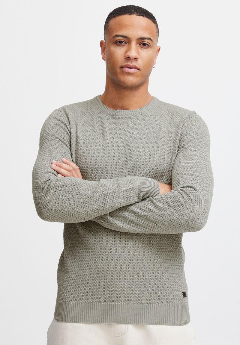 Maglione grigio strutturato con scollatura rotonda, caratterizzato da un motivo a nido d'ape e polsini e orlo a costine.