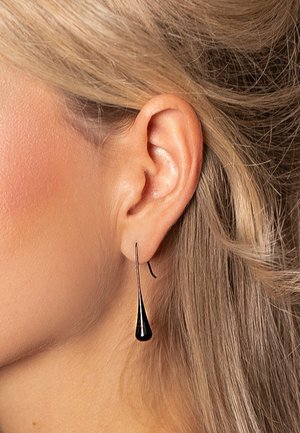 Black teardrop-shaped earrings with a sleek, shiny finish, hanging from a curved hook. Profile view showing attachment at the lobe.