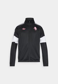 Μαύρο φόρμα τζάκετ με ψηλό γιακά, λευκά μανίκια, ροζ κεντημένα λογότυπα και αντίθετο ροζ σχέδιο. Ελαφρύ ύφασμα, κλείσιμο με φερμουάρ.