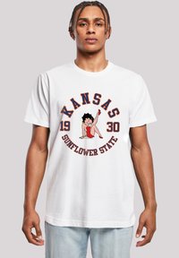 White cotton t-shirt featuring Kansas graphic in red, blue, and black with the text "Kansas 1930 Sunflower State" and a cartoon figure.