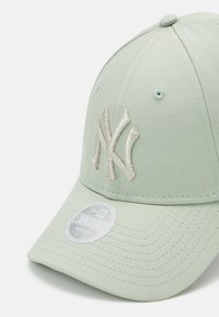 Casquette vert menthe avec une visière incurvée, ornée d'un logo en relief brodé en argent. Comprend une étiquette indiquant qu'il s'agit d'une série New Era 940.