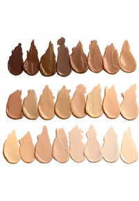 Una fila di vari fondotinta in crema di diverse tonalità, mostrati come strisce spesse e texturizzate, che vanno da un marrone scuro a un beige chiaro e avorio.