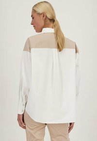Witte shirt met een beige bovenpaneel, met knoopmanchetten en een losse pasvorm. Gemaakt van lichtgewicht stof met een gladde textuur.