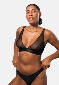 Svart underkläder set med en genomskinlig bralette med djup V-design, justerbara axelband och matchande låg midja bikini. Slätt, lätt tyg.