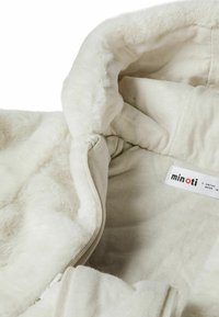 Sudadera de felpa blanca con un interior suave, que cuenta con una cremallera, una capucha forrada y una etiqueta que indica la marca "minoti" para 6 meses.