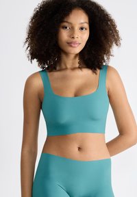 Teal Crop-Top aus glattem Material mit breiten Trägern und quadratischem Ausschnitt, kombiniert mit passenden hoch taillierten Hosen.