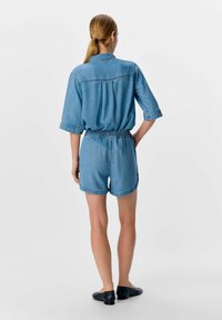 Conjunto de camisa de mezclilla y pantalones cortos en azul claro, con mangas cortas y cinturilla elástica. Textura suave con detalles de costura mínimos.