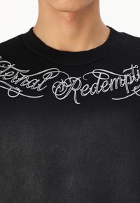Black sweatshirt with crew neckline, featuring white cursive "Eternal Redemption" text across the chest. Soft fabric with a smooth texture.