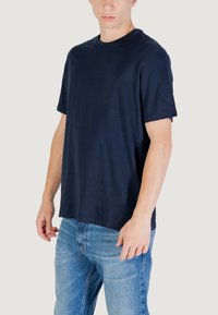 T-shirt in cotone blu navy con maniche corte, scollo rotondo e vestibilità comoda, indossata da un modello maschile abbinata a jeans azzurri.