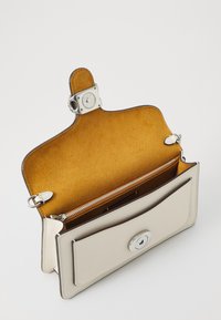 Compact cream leather wallet with a silver snap closure. Interior features a soft mustard lining and a zippered compartment for organization.